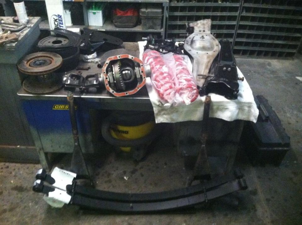 Vehicle differential, brake rotors, and leaf springs on a workbench