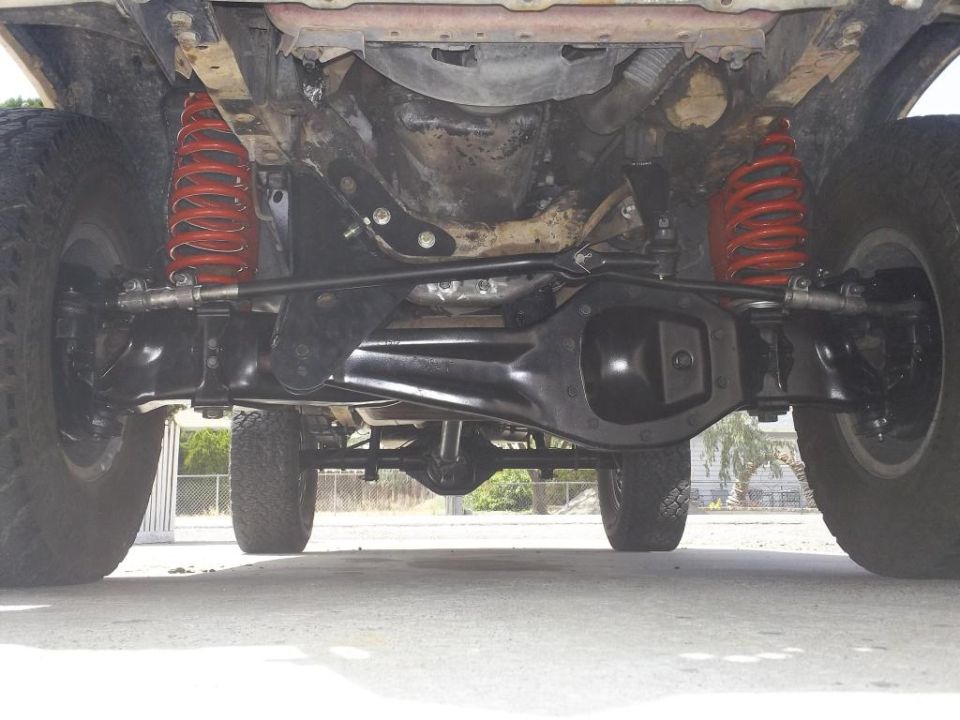 Undercarriage of a vehicle with red coil springs and large tires, viewed from below