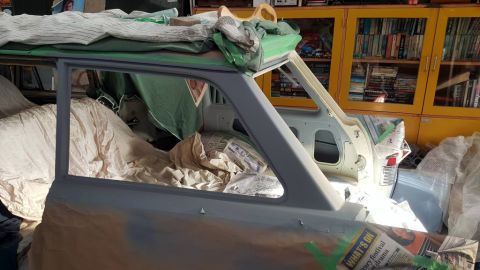 1962 MG B - Side view of a 1962 MG B undergoing restoration, covered in primer and protective materials.