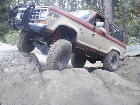 1987 Ford Bronco II - A 1987 Ford Bronco II navigates a challenging rocky terrain with its front-left wheel high in the air.