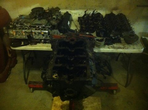 1987 Ford Bronco II - Disassembled engine components are laid out on a table and stand.