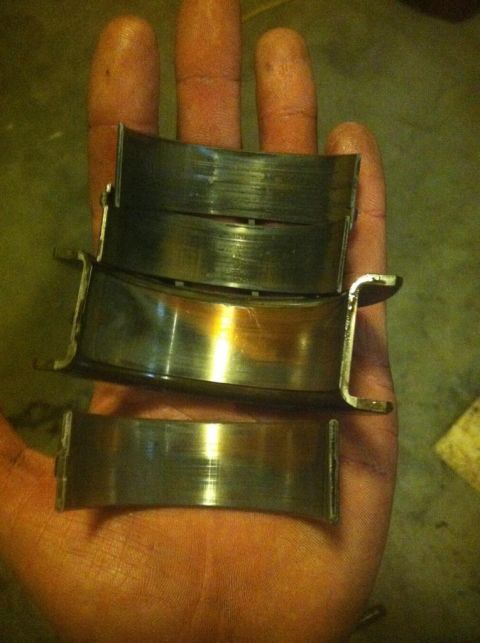 1987 Ford Bronco II - Several used engine bearings are held in a person's hand, showing signs of wear.