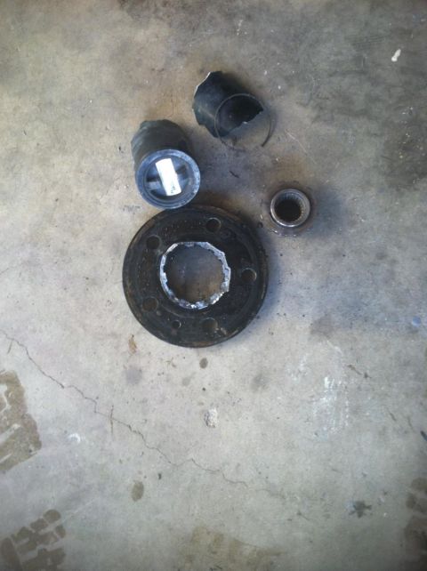 1987 Ford Bronco II - Several automotive parts, including rubber pieces and a metal flange, lie on a concrete surface.