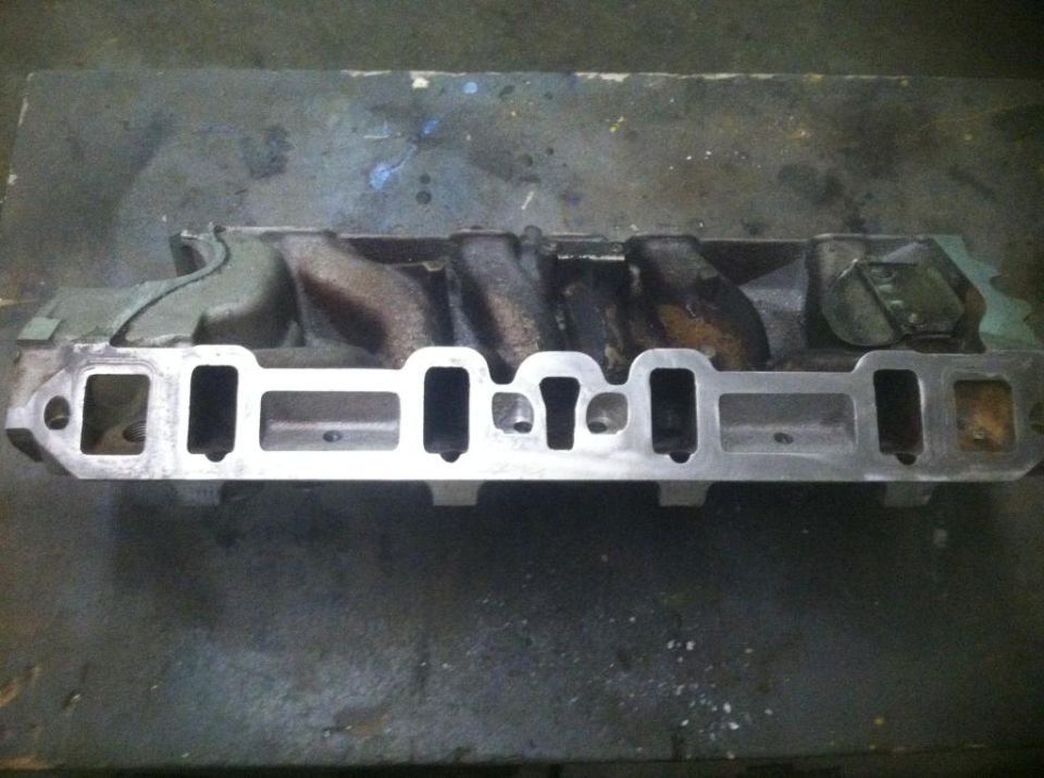 Aluminum intake manifold with six intake ports and two exhaust ports, on a dark surface