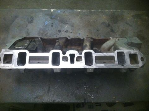 1987 Ford Bronco II - An intake manifold is shown resting on a workbench surface.
