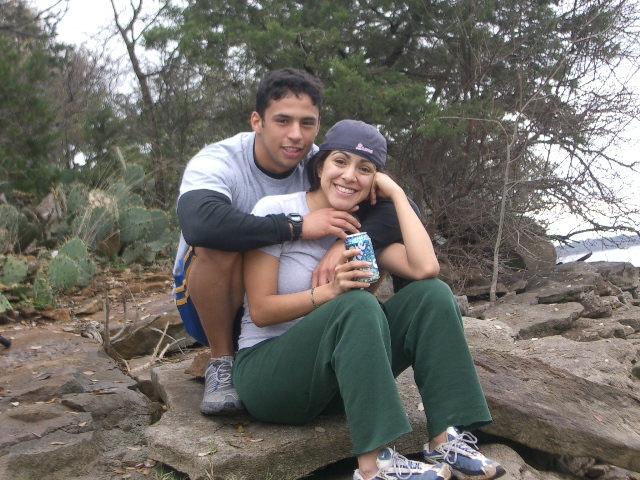 Couple sitting on rocks near water, man has arm around woman
