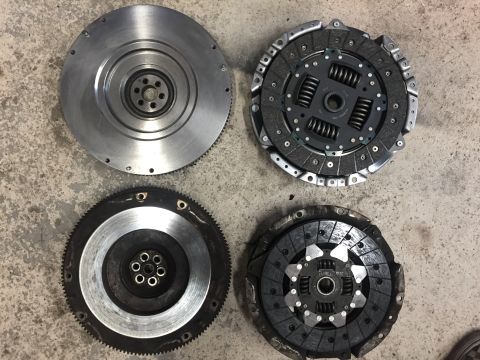1987 Ford Bronco II - A collection of automotive clutch and flywheel components are displayed on a textured floor.