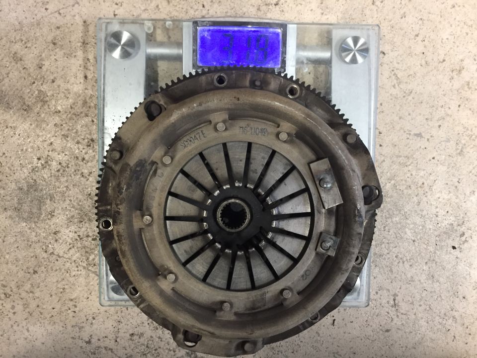 Used clutch pressure plate and flywheel assembly on a workbench scale
