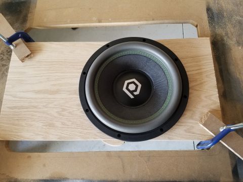 1994 Ford Bronco - Photograph of a subwoofer driver placed on a plywood board during a DIY enclosure build.