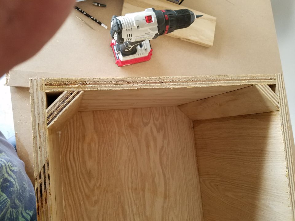 Cordless drill on top of a plywood speaker enclosure being built