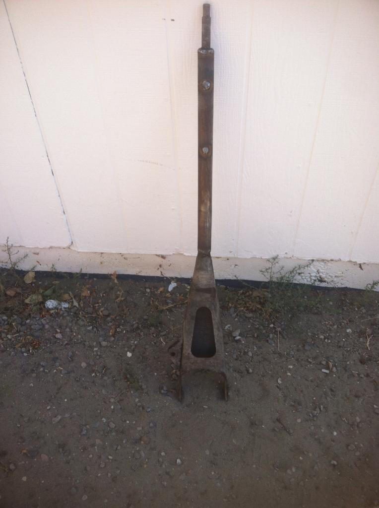 Rusty adjustable metal jack stand with a triangular base and cylindrical top.