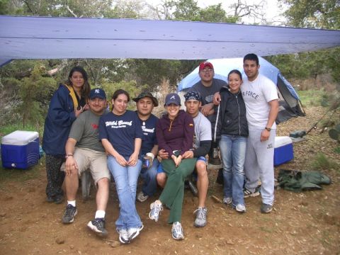 1994 Ford Bronco - A group of friends gathered under a tarp at a campsite, with tents and coolers visible in the background.