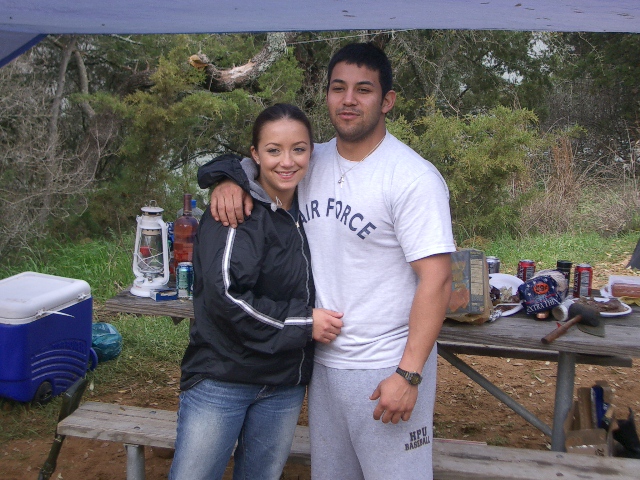 Couple posing at a picnic table with food and drinks