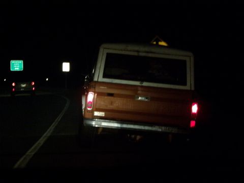 1969 Ford Bronco - Bus rear view at night, showing taillights and yellow and white body.