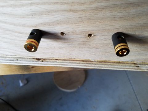 1994 Ford Bronco - Close-up photograph of two gold speaker binding-post connectors mounted in a plywood panel.