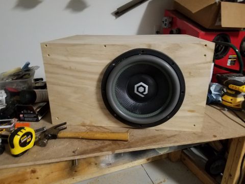 1994 Ford Bronco - Photograph of a single 12-inch subwoofer installed in a raw plywood enclosure, not a technical document.