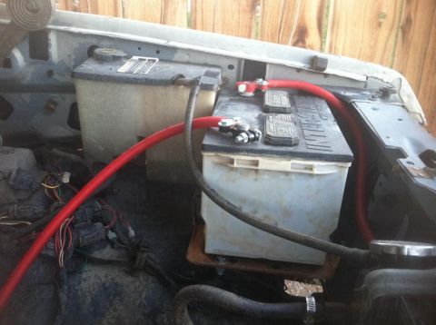 1984 Ford Bronco - The engine bay of a 1984 Ford Bronco shows a dual battery setup with thick red cables connecting the batteries. Various wires and hoses are…