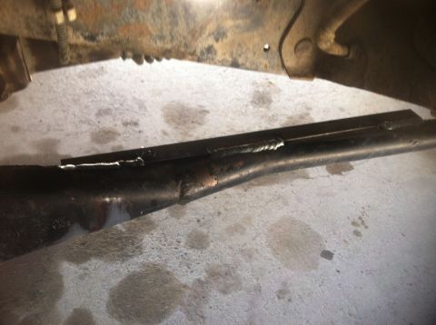 1984 Ford Bronco - A close-up view shows a metal bracket welded onto a black, curved metal tube, likely part of a vehicle's suspension or exhaust system. The…