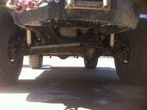 1984 Ford Bronco - The underside of a lifted 4x4 vehicle, likely a truck or SUV, is shown from a low angle. Visible components include the front suspension, s…
