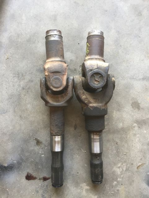 1984 Ford Bronco - A comparison of two driveshaft U-joints is shown, resting on a concrete floor.