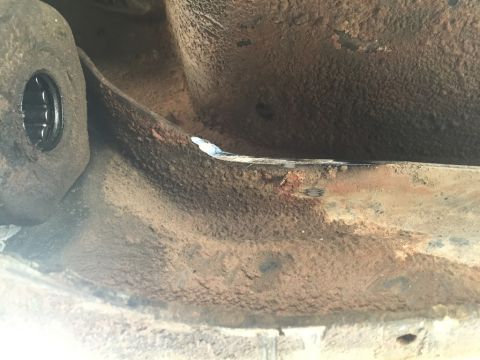 1984 Ford Bronco - Close-up view of a heavily rusted vehicle frame component, showing signs of wear and tear.