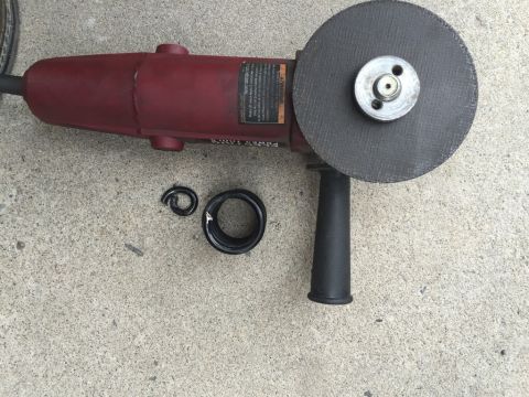 1984 Ford Bronco - A red angle grinder and its detached parts lie on a concrete surface, suggesting a repair or modification.