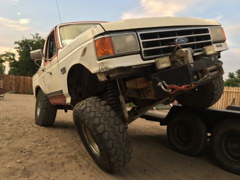 1984 Ford Bronco - This Ford truck, likely from the late 1980s, is being loaded onto a trailer with a winch system.