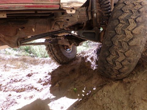 1984 Ford Bronco - Close-up of the undercarriage and suspension of a vehicle on an off-road trail.