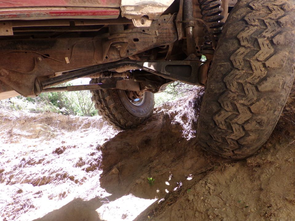 Undercarriage view of a red vehicle with large tires on a dirt trail