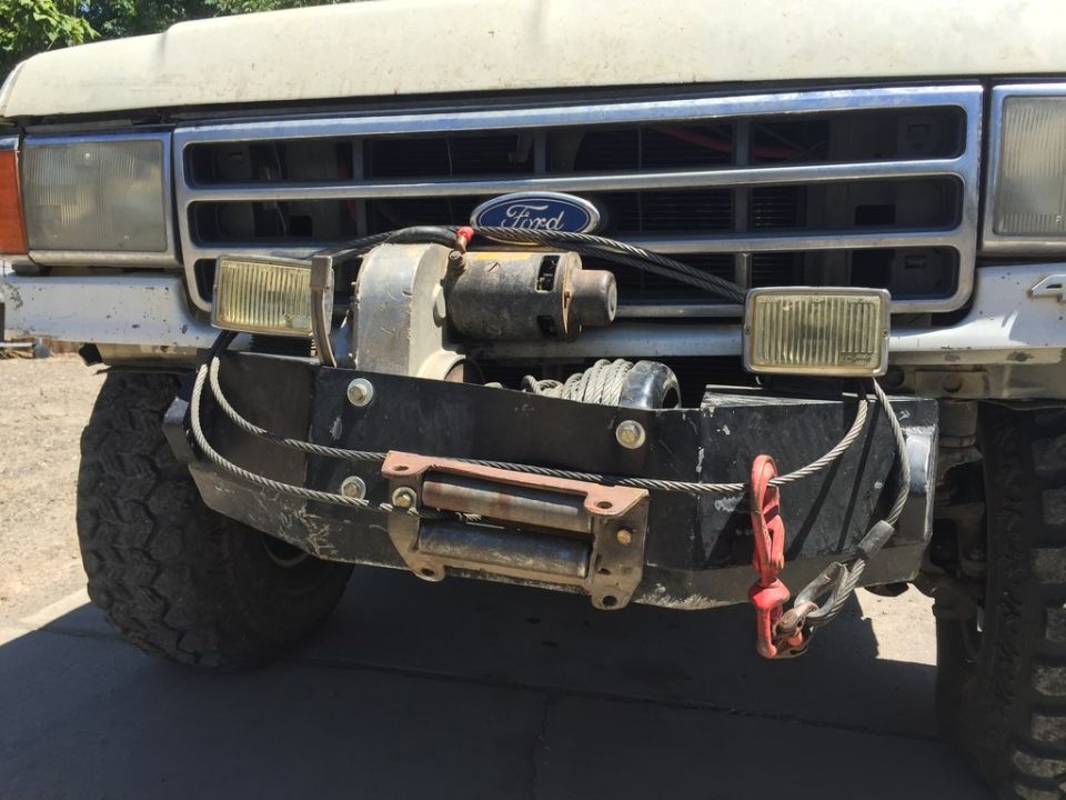 Front view of a white Ford Bronco with a winch and tow hooks on the bumper.