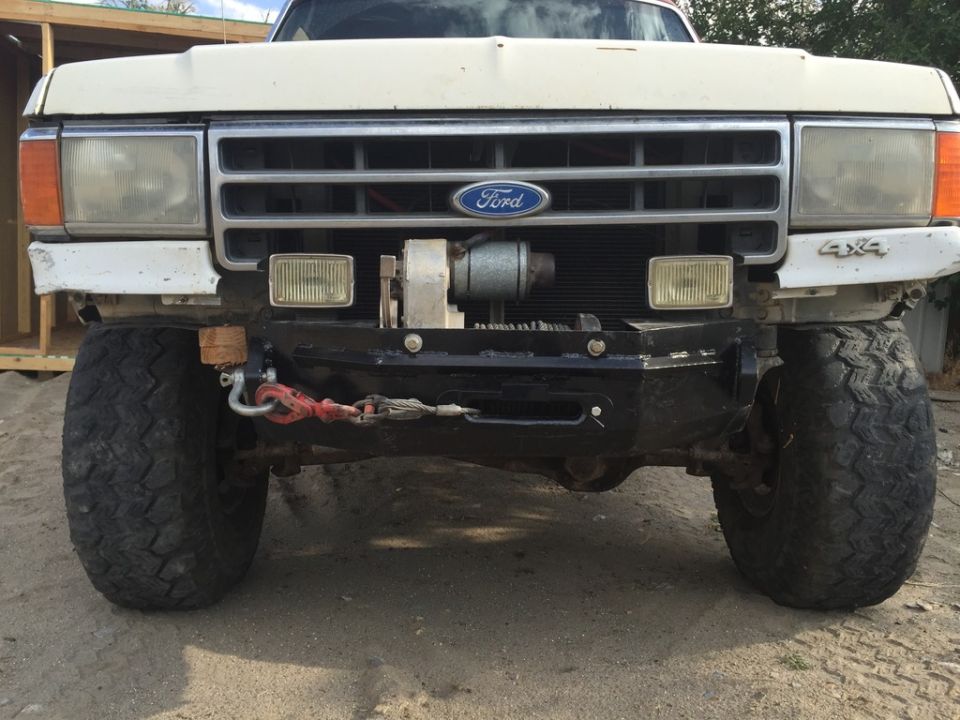White Ford Bronco front end with winch, off-road tires, and 4x4 badging.