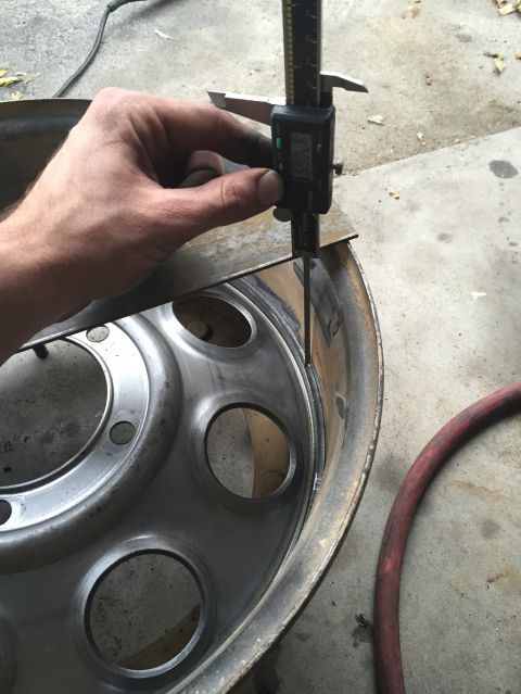 1984 Ford Bronco - A person is using a digital caliper to measure the lip of a large metal wheel, likely from a truck or heavy equipment. The wheel has severa…