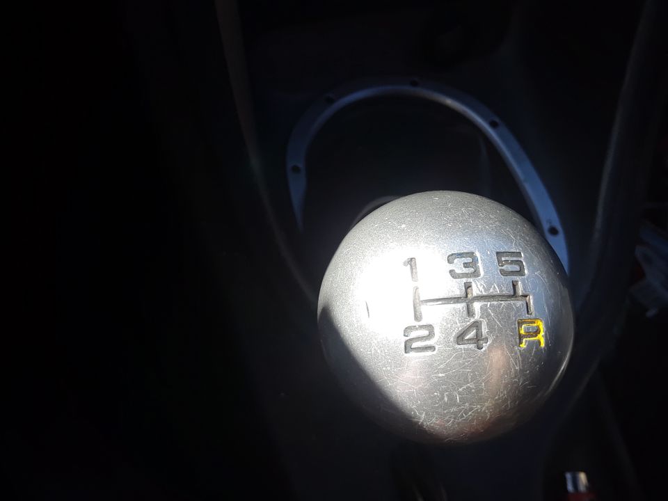 Aluminum 5-speed shift knob with engraved shift pattern, R marked in yellow, in a dark car interior