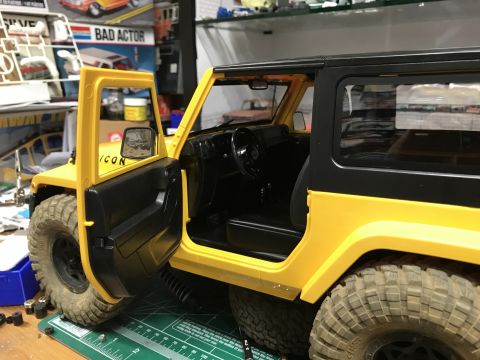 1989 Ford Bronco - A yellow Jeep Wrangler with its driver's door ajar is displayed on a cutting mat.