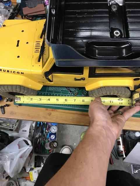 1989 Ford Bronco - Measuring the wheelbase of a yellow RC Jeep Rubicon model on a cutting mat.