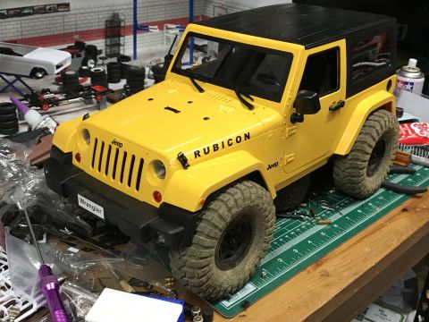 1989 Ford Bronco - A yellow Jeep Wrangler Rubicon toy model sits on a cutting mat surrounded by hobbyist tools and parts.