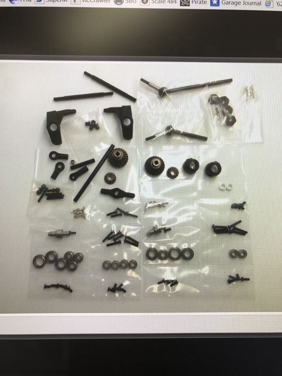 RC car parts laid out in plastic bags, including gears, shafts, and bearings