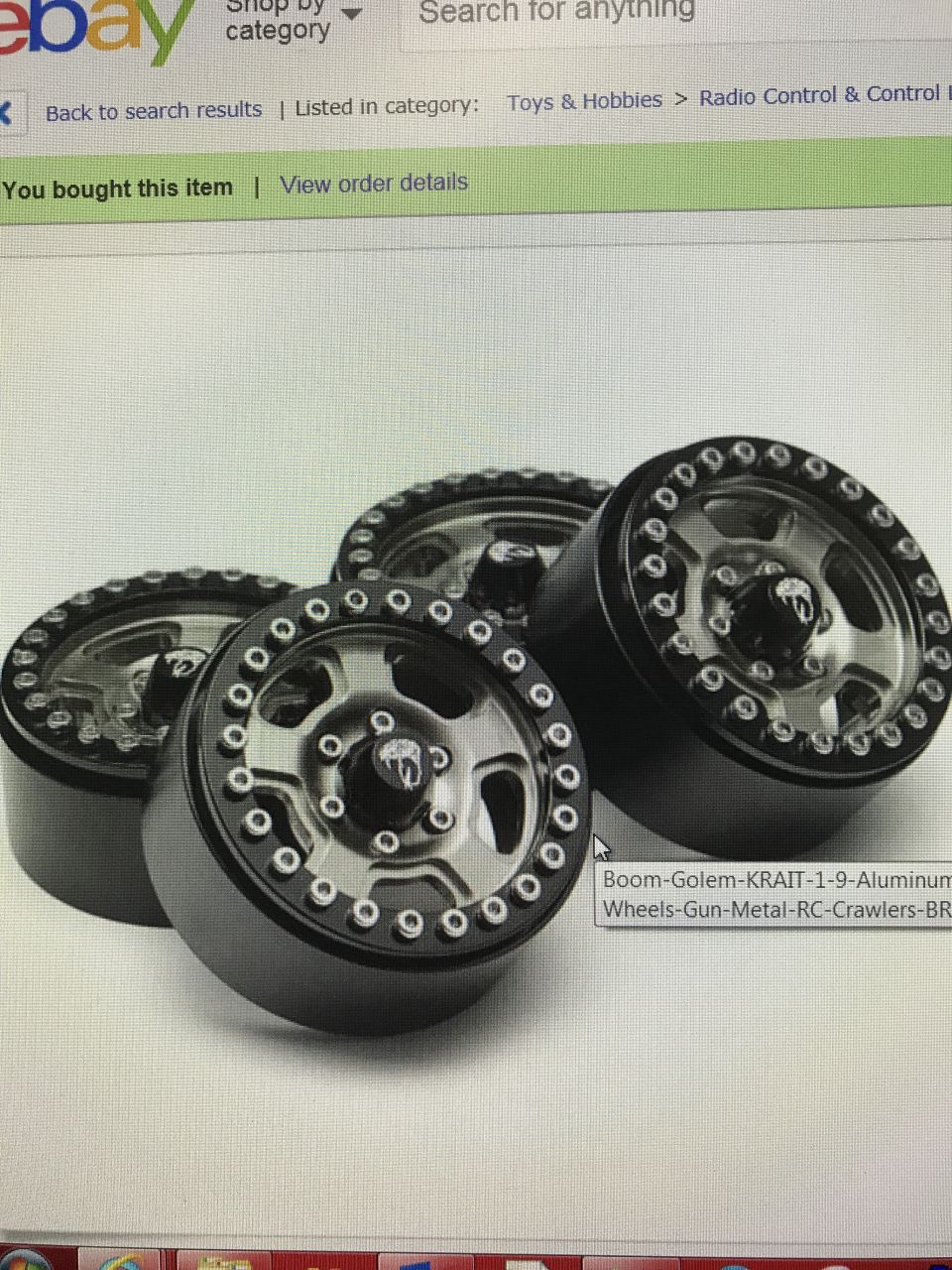 Four black and silver RC crawler wheels with beadlock rings, viewed from a slight angle