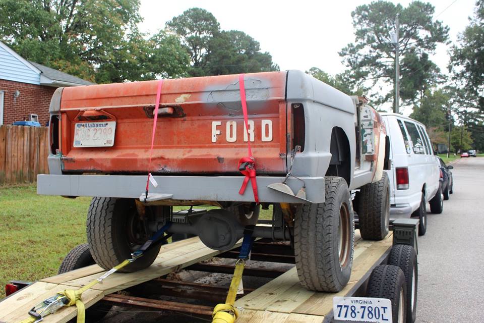 1966 Ford Bronco on a trailer, orange tailgate with white FORD lettering, gray primer body, Alabama license plate