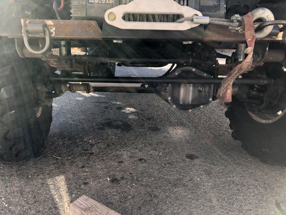 Undercarriage of an off-road vehicle showing the front axle, suspension, and a winch mounted on the front