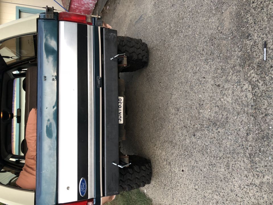 Dark green and white Ford Bronco rear with a license plate and large tires