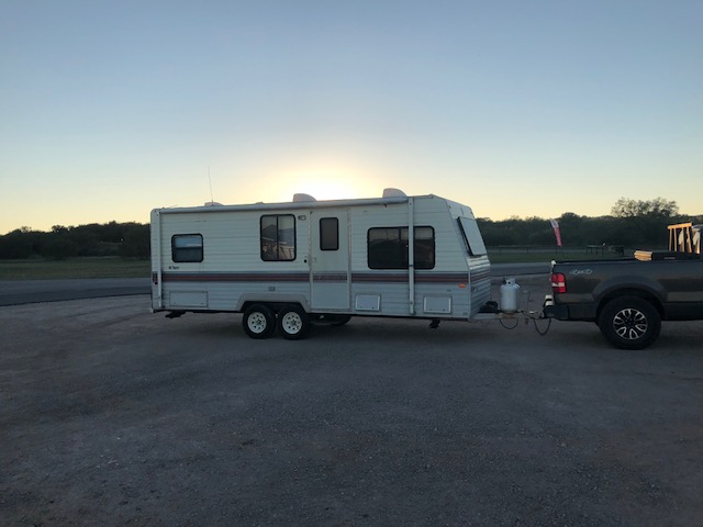 Travel trailer parked next to a pickup truck at dusk