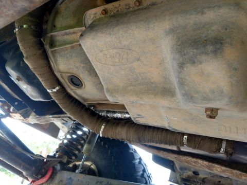 1992 Ford Bronco - Underbody view of exhaust pipes wrapped in heat tape, with a Ford-branded transmission pan visible.