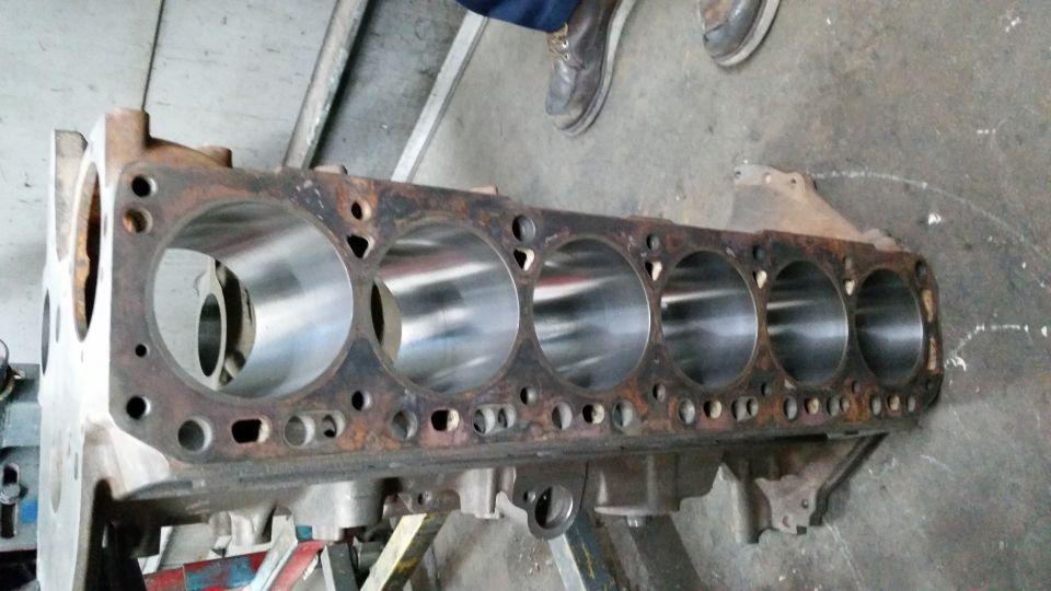 Engine block with six cylinders, showing rust and wear