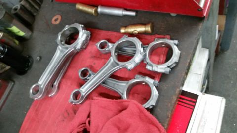 1981 Ford Bronco - Engine connecting rods are laid out on a red cloth next to various tools on a workbench.