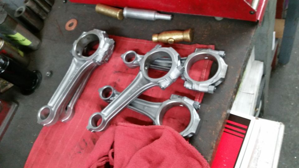 Engine connecting rods on a red cloth with tools on a workbench