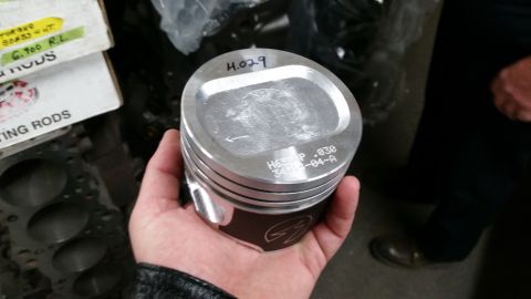 1981 Ford Bronco - A close-up of an engine piston held in a hand, with part numbers visible on its surface.