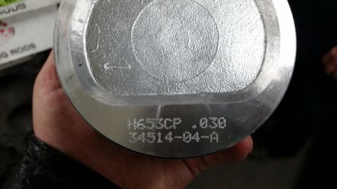 1981 Ford Bronco - A close-up view of a silver piston with engraved markings, held by a person's hand.