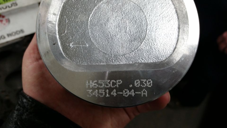 Silver piston with engraved text H653CP .030 34514-04-A, held in hand