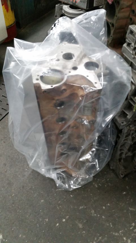 1981 Ford Bronco - An engine block, likely for a Ford vehicle, is covered in protective plastic wrap in a workshop setting.